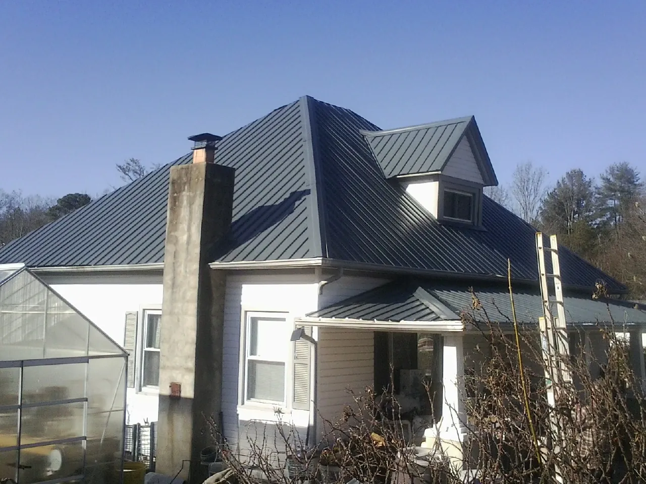 Dark blue standing seam metal roof on a white farmhouse with dormer — Slate & Tile Roof Repair by Roofing Brothers in Bethany