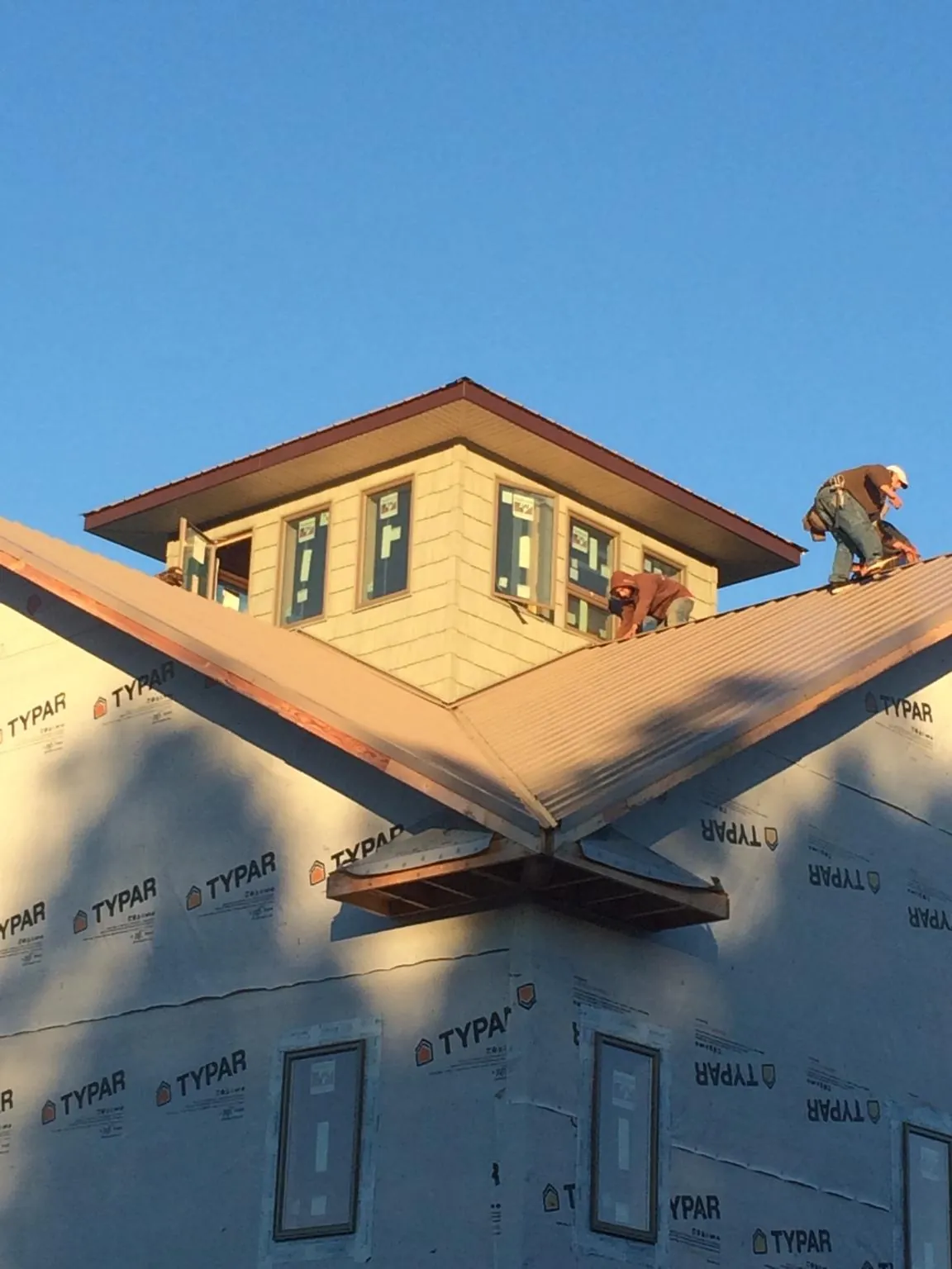 Roofers working around a rooftop cupola on a new metal roof at sunset — Roof Waterproofing in Bethany by Roofing Brothers